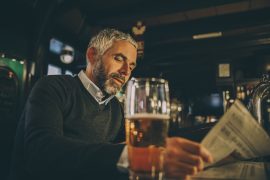 Man in pub with a beer reading the paper